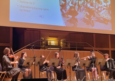 Zdjęcie grupy uczniów grających na instrumentach w szkole muzycznej