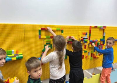 dzieci z przedszkola na warsztatach ekologicznych w szkole buduja na ścianie z klocków