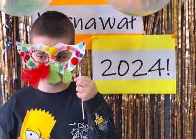 Uczeń w masce karnawałowej na tle dekoracji karnawał 2024